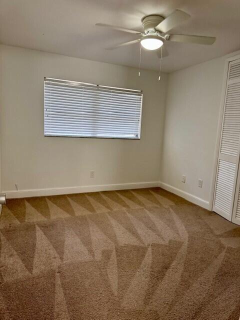 carpeted spare room with a ceiling fan and baseboards