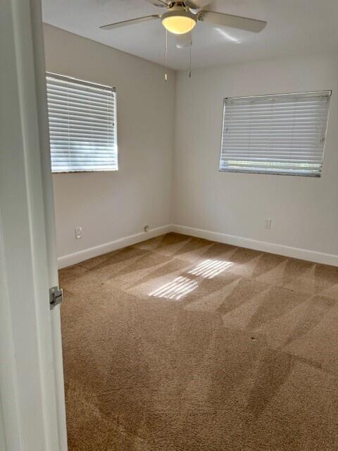 empty room featuring a ceiling fan, baseboards, and carpet floors