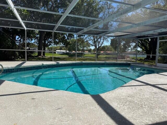 pool featuring glass enclosure and a patio area