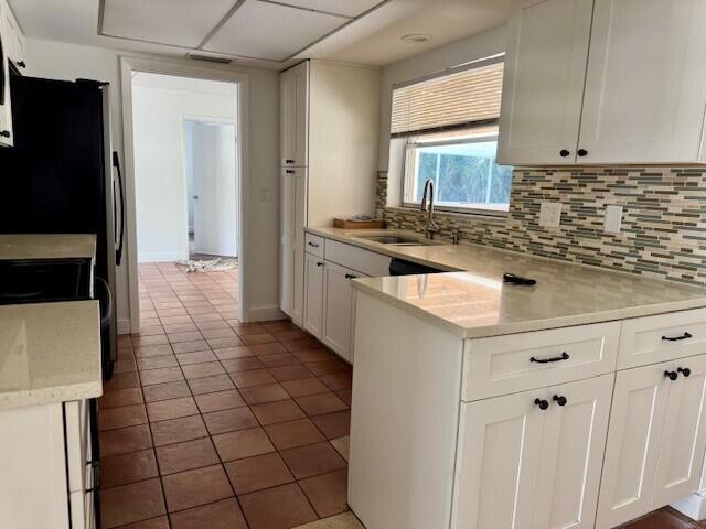 kitchen featuring a sink, decorative backsplash, white cabinets, and light countertops