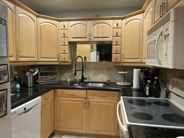 kitchen with decorative backsplash, white appliances, dark stone counters, and a sink