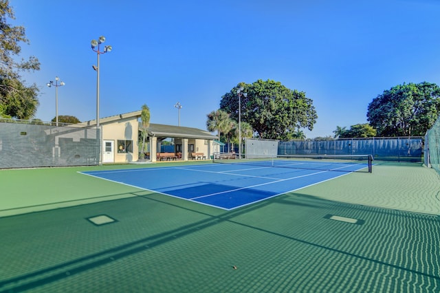 view of tennis court featuring community basketball court and fence