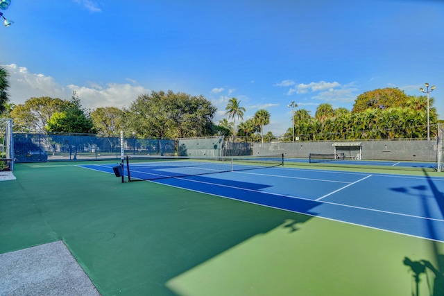 view of tennis court featuring community basketball court and fence