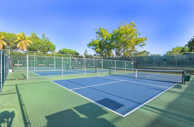 view of tennis court with community basketball court and fence