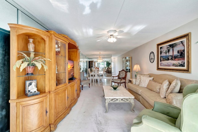 living area with ceiling fan with notable chandelier and light colored carpet