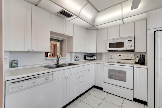 kitchen featuring visible vents, white appliances, light countertops, and a sink