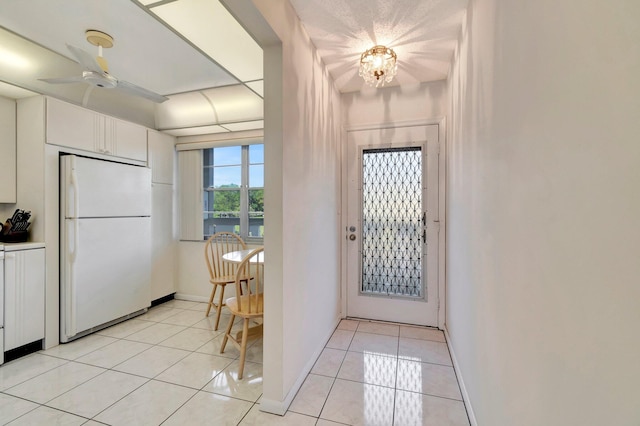 foyer entrance featuring light tile patterned flooring, a ceiling fan, and baseboards