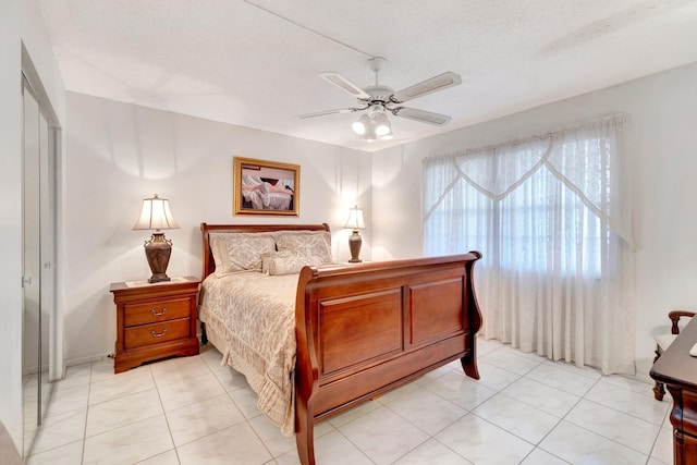 bedroom featuring ceiling fan, light tile patterned flooring, and a textured ceiling