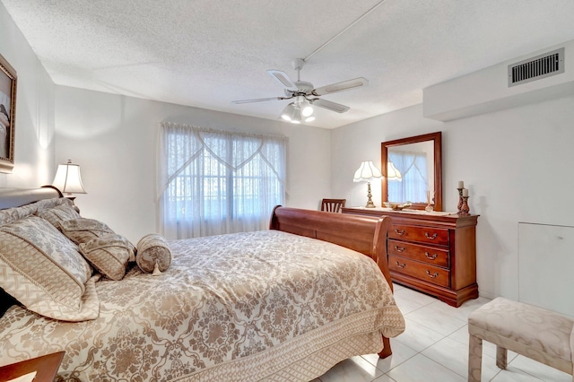 bedroom featuring light tile patterned flooring, visible vents, a textured ceiling, and ceiling fan