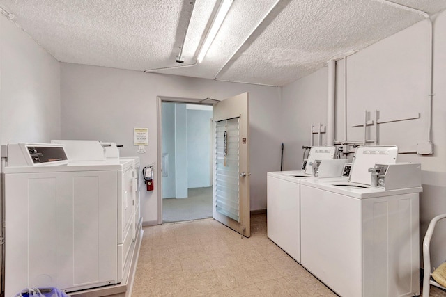 community laundry room featuring washer and dryer, a textured ceiling, and light floors