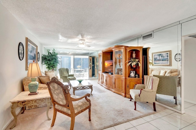 living room featuring visible vents, a textured ceiling, light tile patterned flooring, and a ceiling fan