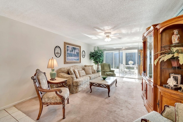 living area with light tile patterned floors, baseboards, ceiling fan, a textured ceiling, and light carpet