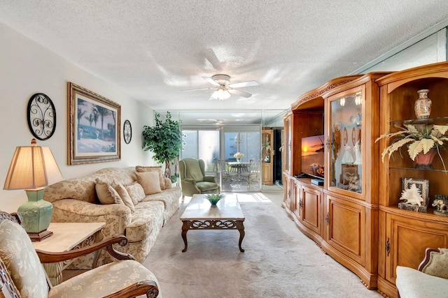 living area featuring light carpet, a textured ceiling, and ceiling fan