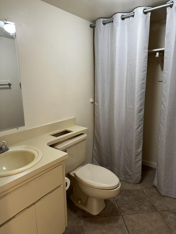 full bath with tile patterned floors, curtained shower, toilet, and vanity