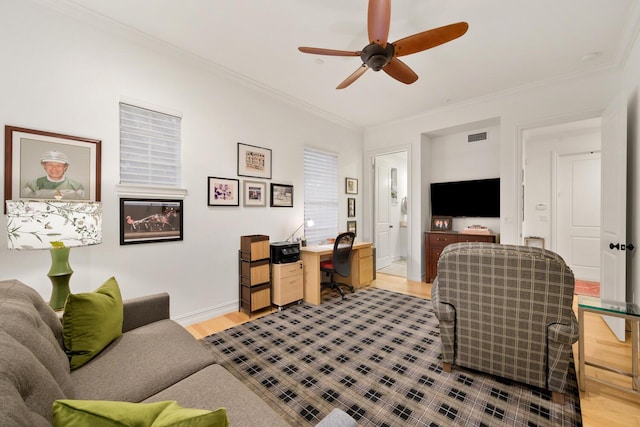 office space with visible vents, ornamental molding, a ceiling fan, light wood-style floors, and baseboards