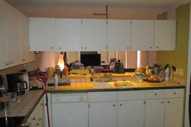 kitchen featuring tile countertops, white cabinets, white dishwasher, and a sink