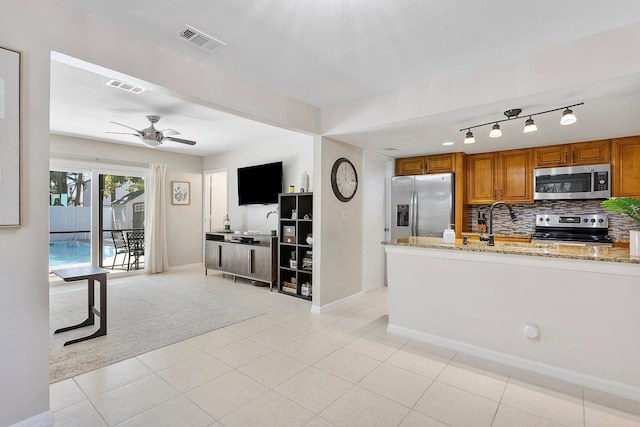 kitchen featuring light stone counters, visible vents, brown cabinets, and appliances with stainless steel finishes