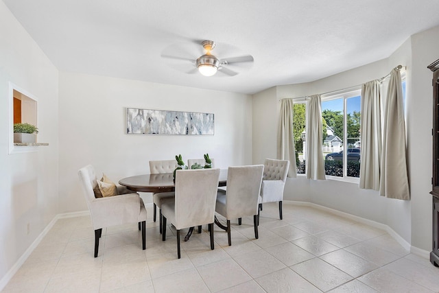 dining area featuring light tile patterned floors, a ceiling fan, and baseboards