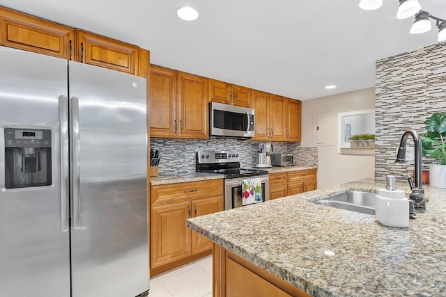 kitchen with backsplash, light stone counters, light tile patterned floors, stainless steel appliances, and a sink