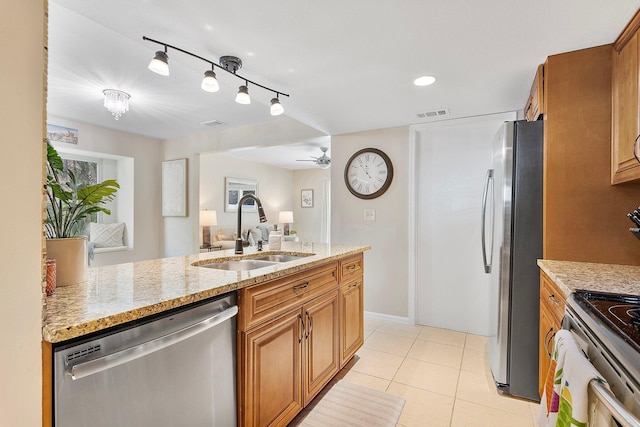 kitchen with light tile patterned floors, brown cabinetry, appliances with stainless steel finishes, and a sink