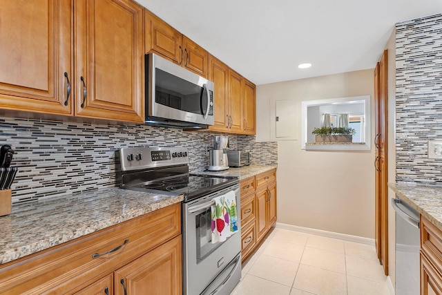 kitchen featuring light stone counters, baseboards, light tile patterned flooring, appliances with stainless steel finishes, and backsplash