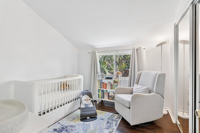 bedroom featuring a nursery area, wood finished floors, and baseboards