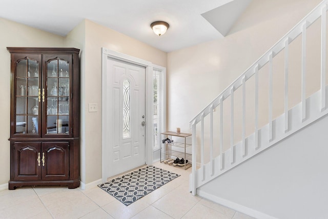 tiled foyer with baseboards and stairs