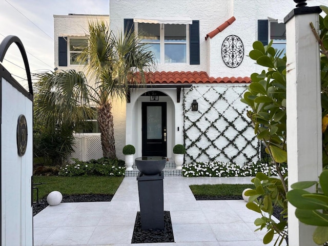 doorway to property featuring a tiled roof and stucco siding