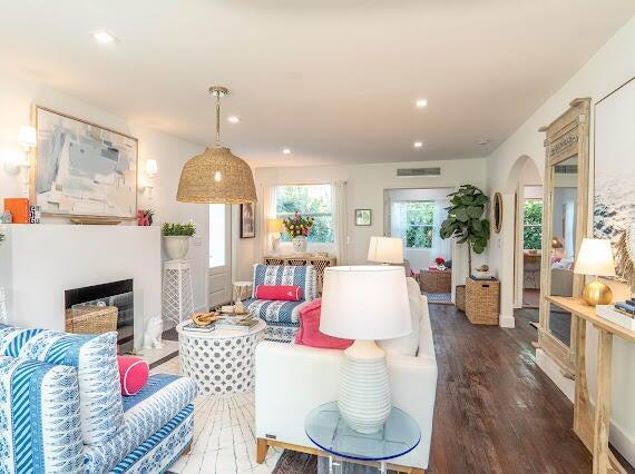 living area featuring arched walkways, recessed lighting, a fireplace, and wood finished floors