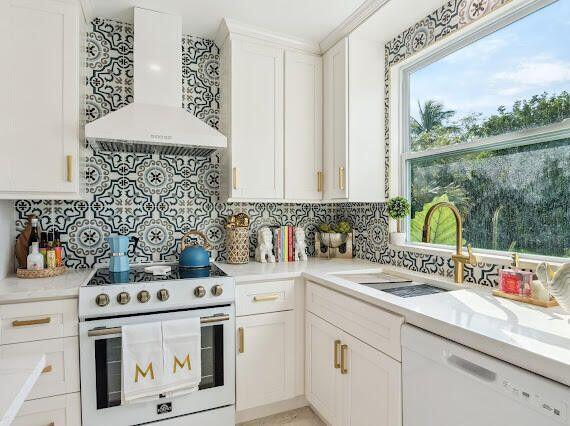 kitchen with ventilation hood, light countertops, white cabinets, white appliances, and a sink