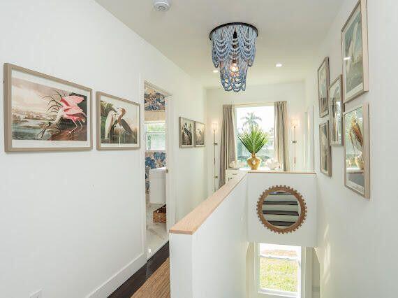 hallway featuring a healthy amount of sunlight, an upstairs landing, baseboards, and a chandelier