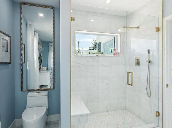 bathroom featuring toilet, baseboards, and a marble finish shower