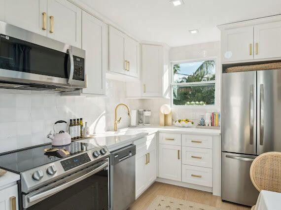 kitchen with white cabinetry, light countertops, tasteful backsplash, and appliances with stainless steel finishes