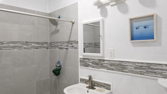 bathroom with a sink, tiled shower, and tasteful backsplash