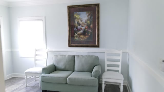 living area with crown molding, wood finished floors, and baseboards