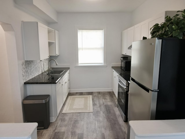 kitchen with light wood-style flooring, a sink, appliances with stainless steel finishes, white cabinets, and baseboards