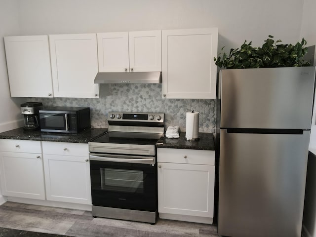 kitchen featuring dark stone countertops, white cabinets, under cabinet range hood, appliances with stainless steel finishes, and tasteful backsplash