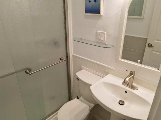 bathroom featuring toilet, a stall shower, and a sink