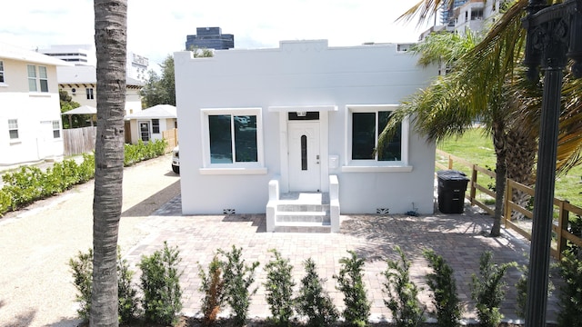 view of front of home featuring stucco siding, a chimney, and fence