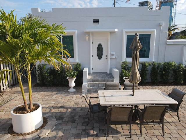 view of exterior entry with stucco siding, outdoor dining area, and a patio area