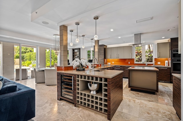 kitchen featuring a sink, a spacious island, open floor plan, light countertops, and decorative backsplash