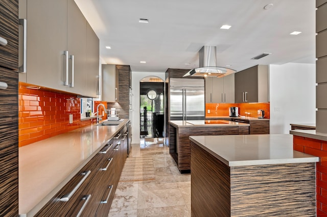 kitchen featuring built in refrigerator, modern cabinets, a sink, a center island, and island range hood