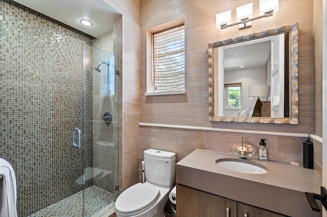 bathroom with vanity, toilet, tile walls, and a shower stall