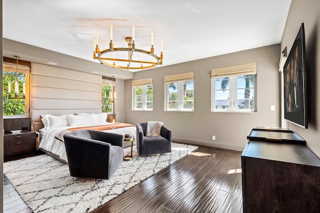 bedroom featuring a notable chandelier, baseboards, and wood finished floors