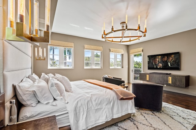 bedroom with baseboards, an inviting chandelier, and wood finished floors