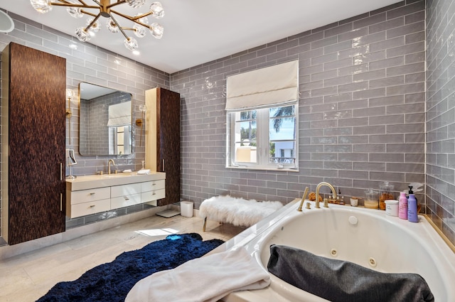 bathroom with vanity, an inviting chandelier, a tub with jets, and tile walls