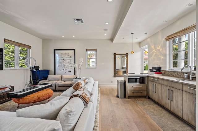 living area with a wealth of natural light, visible vents, recessed lighting, and light wood finished floors