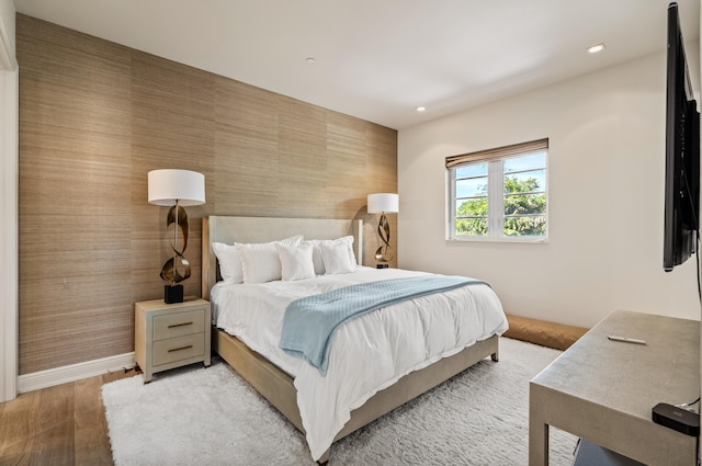 bedroom with wallpapered walls, an accent wall, baseboards, light wood-type flooring, and recessed lighting