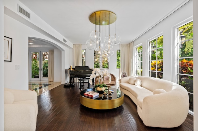 living room with wood finished floors, plenty of natural light, arched walkways, and visible vents