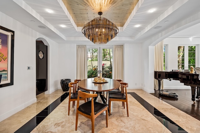 dining area featuring arched walkways, plenty of natural light, baseboards, and a tray ceiling